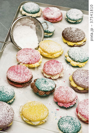 Various macaroons dusted with icing sugar on a baking tray 37541810