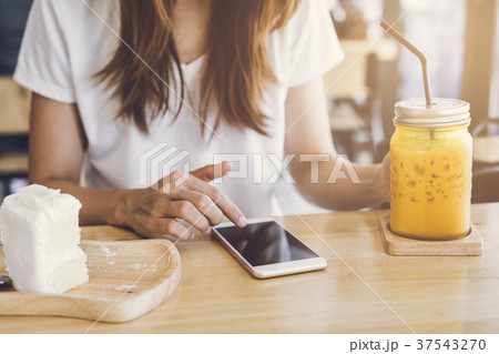 Young woman using smart phone and eating cake 37543270