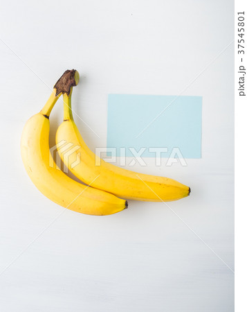 Two bananas on white with blue card 37545801