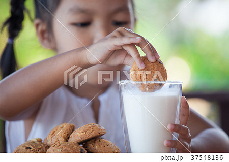asian little child girl eating cookie with milk asian little child girl eating cookie with milk 37548136