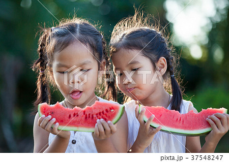 Two asian little child girls eating watermelon Two asian little child girls eating watermelon 37548247