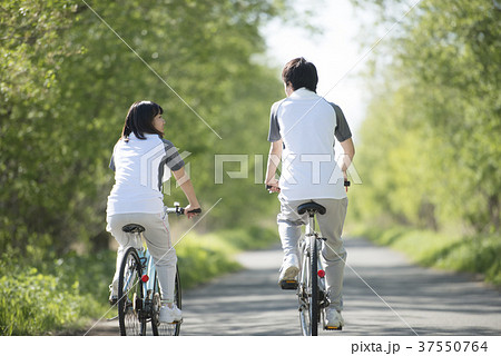 自転車に乗るカップルの後姿の写真素材