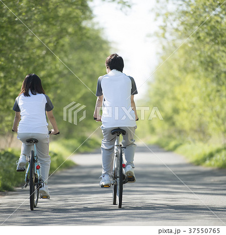 自転車に乗るカップルの後姿の写真素材