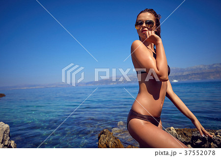 Young adult slim woman in 20s posing on rocks on adriatic sea co Young adult slim woman in 20s posing on rocks on adriatic sea co 37552078
