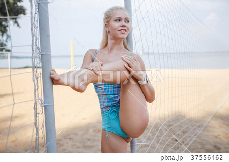 Blonde girl is posing on the beach in a blue suit Blonde girl is posing on the beach in a blue suit 37556462