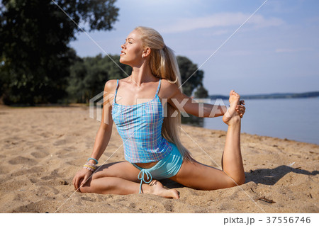 Blonde girl in a blue suit is doing yoga on beach 37556746