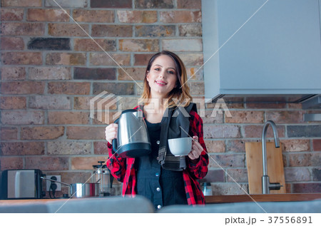 Young redhead pregnant woman with kittle and cup 37556891