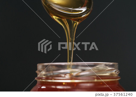 scooping organic honey with spoon from glass jar scooping organic honey with spoon from glass jar 37561240