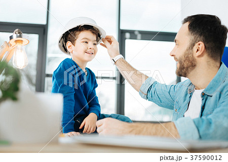 Loving father putting a hard hat on his son 37590012