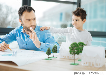 Little boy attracting fathers attention while he 37590260