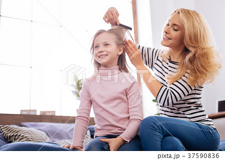 Cheerful mother combing her daughters hair 37590836