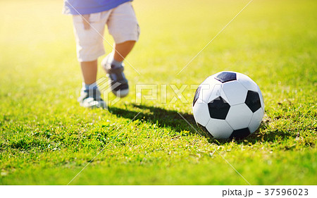 Little boy playing football on the field with 37596023