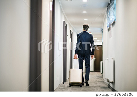 Mature businessman walking with luggage in a hotel Mature businessman walking with luggage in a hotel 37603206