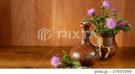 Oil and flowers of milk thistle on wooden . 37605999
