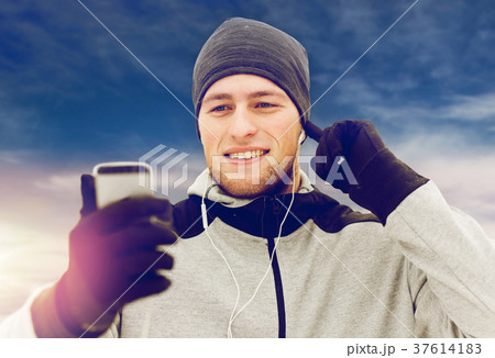 happy man with earphones and smartphone in winter happy man with earphones and smartphone in winter 37614183