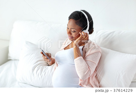 pregnant woman in headphones with smartphone 37614229