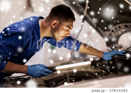 mechanic man with lamp repairing car at workshop 37614393