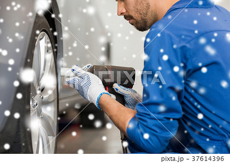 auto mechanic with screwdriver changing car tire auto mechanic with screwdriver changing car tire 37614396