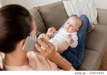mother with baby calling on smartphone at home mother with baby calling on smartphone at home 37614441