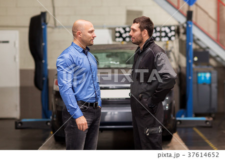 auto mechanic talking to customer at car shop auto mechanic talking to customer at car shop 37614652