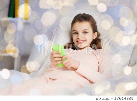 happy girl lying in bed with smartphone at home 37614839