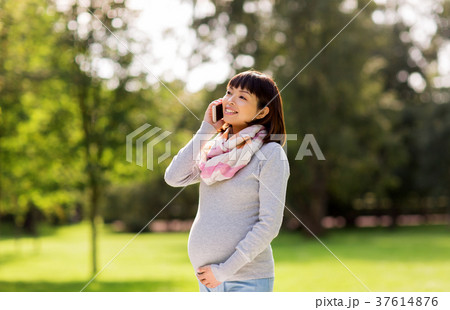 pregnant asian woman calling on smartphone at park 37614876