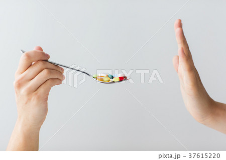 close up of female hand holding spoon with pills 37615220