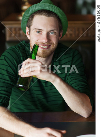 man drinking beer from green bottle at bar or pub man drinking beer from green bottle at bar or pub 37616009