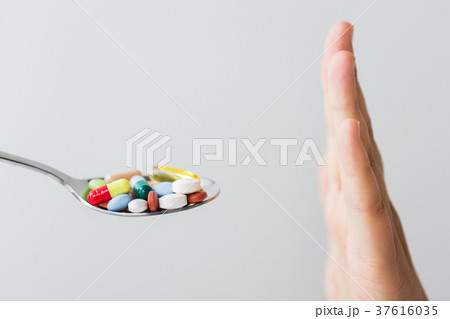 close up of female hand holding spoon with pills 37616035