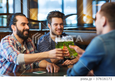 male friends drinking green beer at bar or pub 37616171