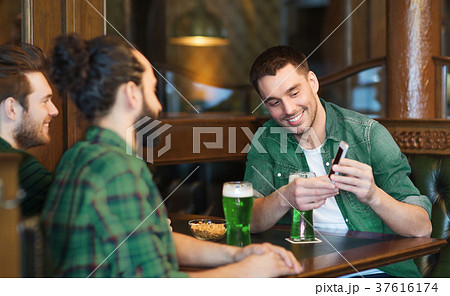 friends with smartphone drinking green beer at pub friends with smartphone drinking green beer at pub 37616174