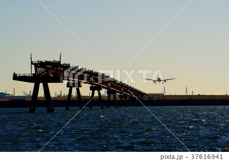 海上の誘導灯の先端と滑走路へ降下する旅客機　c 海面広め 37616941