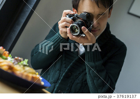 カフェで食べ物を撮影する男性 37619137