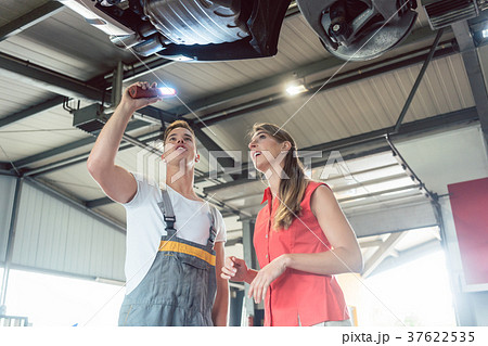 Reliable auto mechanic checking the car of a woman 37622535