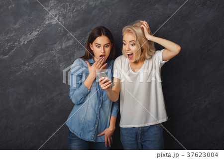 Surprised female friends using smartphone at dark Surprised female friends using smartphone at dark 37623004