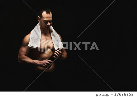 Male bodybuilder drinking water after workout 37636358