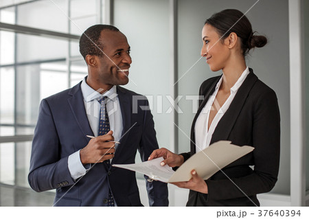 Positive colleagues are standing with documents 37640394