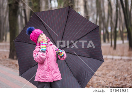 Little  girl walking under umbrella in a park 37641982