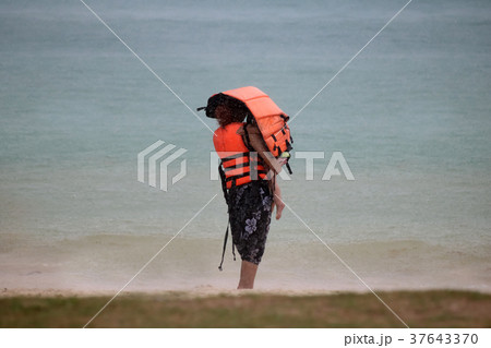 Tourists with raincoat or Life jacket on the beach 37643370