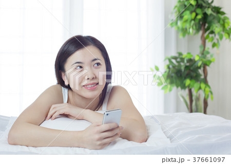 ベットでスマホを操作する若い女性 ベットでスマホを操作する若い女性 37661097