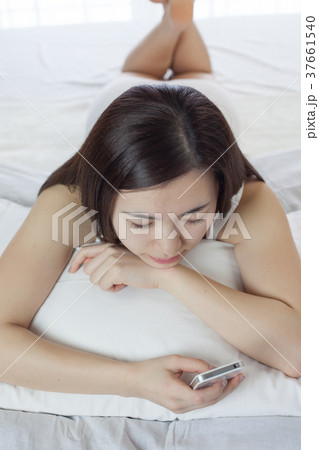 ベットでスマホを操作する若い女性 ベットでスマホを操作する若い女性 37661540