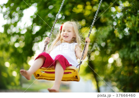 Cute little girl having fun on a playground outdoors on warm summer day 37666460