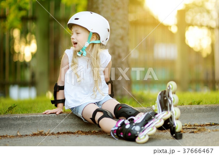Pretty little girl learning to roller skate on beautiful summer day in a park 37666467