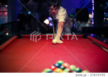 Young handsome man playing in pool at night bar Young handsome man playing in pool at night bar 37670795