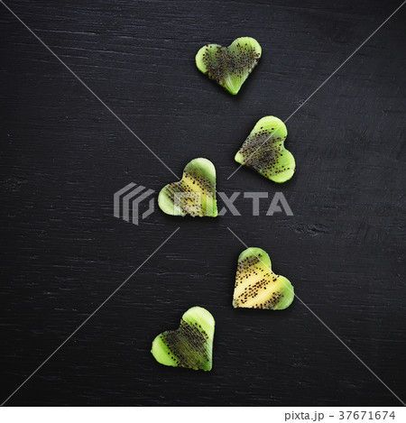 Hearts of kiwi fruit with confetti on black back 37671674