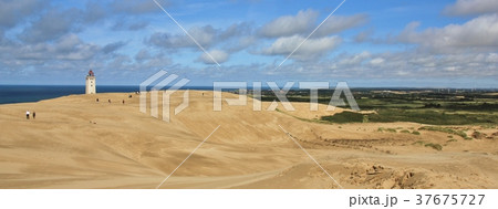 Lighthouse slowly disappearing under asand dune. Lighthouse slowly disappearing under asand dune. 37675727