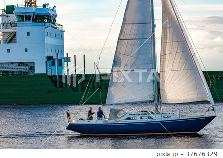 Blue sailboat against cargo ship Blue sailboat against cargo ship 37676329