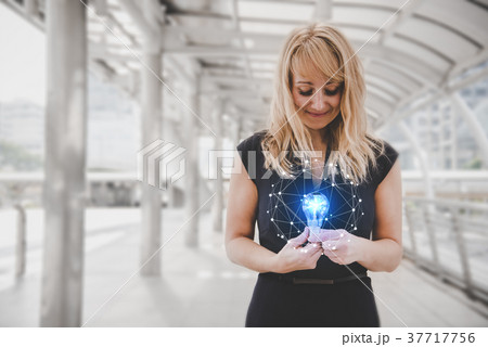 Blonde hair woman holding and looking at Blue light bulb with br 37717756