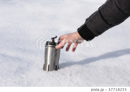 A man's hand reaches for a thermos with hot coffee 37718255