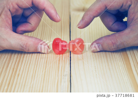Two Hands will touch heart candy on wood plate Two Hands will touch heart candy on wood plate 37718681